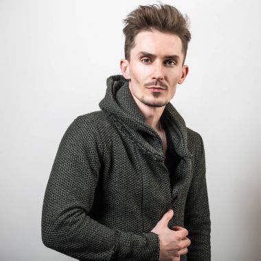 Yakışıklı sportif delikanlı koyu yeşil kapşonlu gri studio arka planı poz.