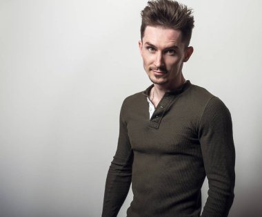 Yakışıklı sportif delikanlı yeşil t-shirt poz gri studio arka planı.