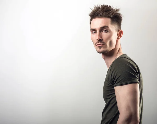 Handsome young sporty man in green t-shirt pose against gray studio background. — Stock Photo, Image