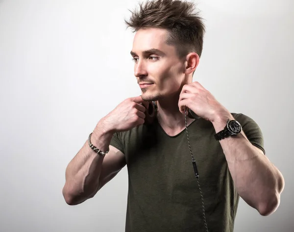 Handsome friendly sporty man in green t-shirt listening music against gray studio background. — Stock Photo, Image