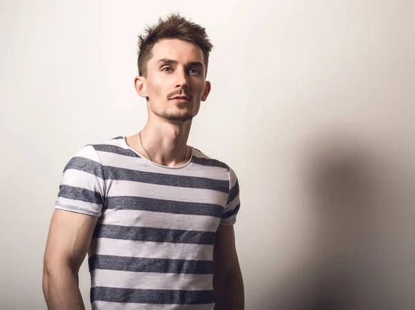 Handsome young man in striped shirt pose against gray studio background. — Stock Photo, Image