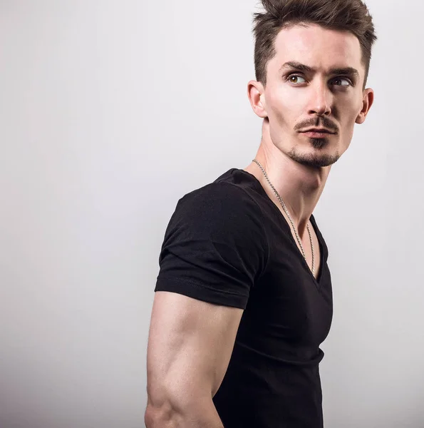 Bonito jovem desportista em preto t-shirt pose contra fundo estúdio cinza . — Fotografia de Stock