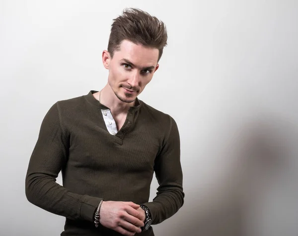 Hombre deportivo joven guapo en camiseta verde posan sobre fondo gris estudio . — Foto de Stock