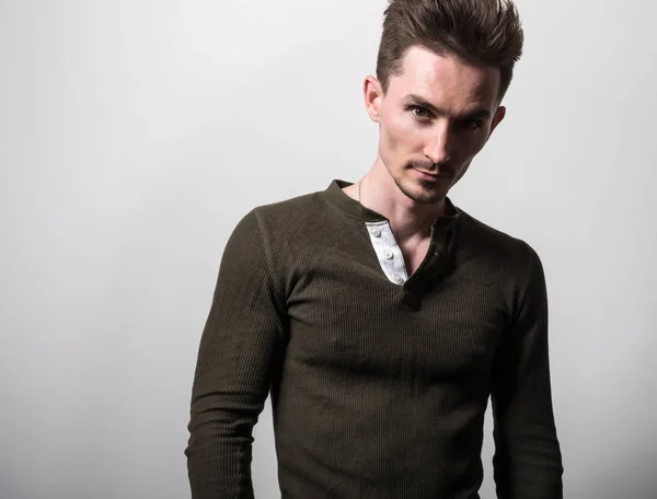 Hombre deportivo joven guapo en camiseta verde posan sobre fondo gris estudio . — Foto de Stock