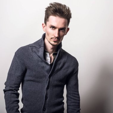 Yakışıklı zarif delikanlı gri switer poz studio arka planı.