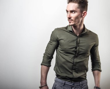 Zarif yakışıklı genç Yeşil gömlekli poz gri studio arka planı.