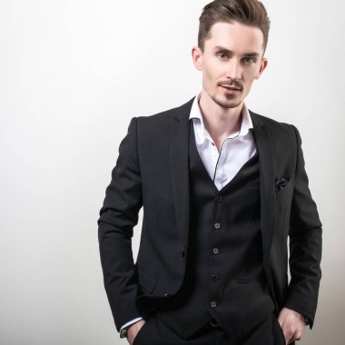 Zarif yakışıklı genç siyah şık klasik kostüm poz studio arka planı.