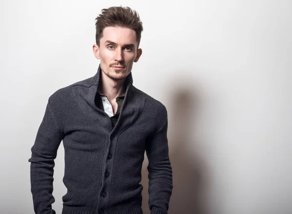 Guapo joven elegante hombre en gris cambiador pose contra fondo de estudio . —  Fotos de Stock