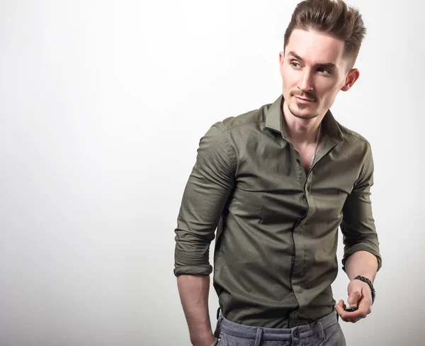 Schöner junger eleganter Mann in grünem Hemd posiert vor grauem Studiohintergrund. — Stockfoto