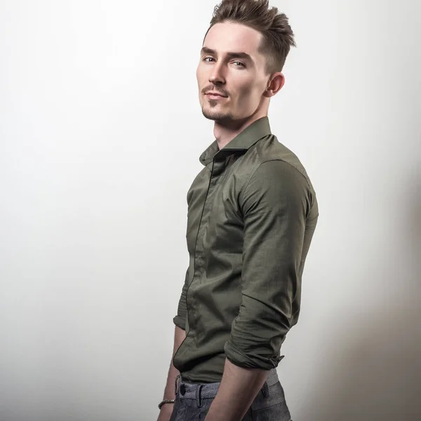 Handsome young elegant man in green shirt pose against gray studio background. — Stock Photo, Image