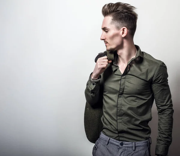 Beau jeune homme élégant en veste vert foncé pose sur fond de studio gris . — Photo