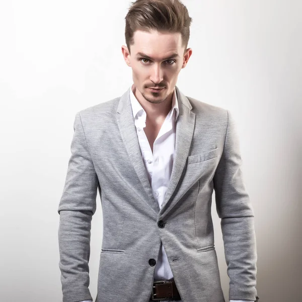 Handsome young elegant man in grey jacket pose against studio background. — Stock Photo, Image