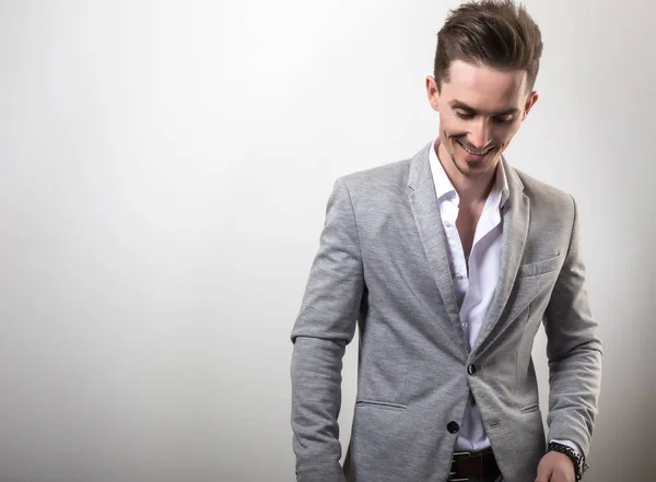 Guapo joven elegante hombre en gris chaqueta pose sobre fondo de estudio . —  Fotos de Stock