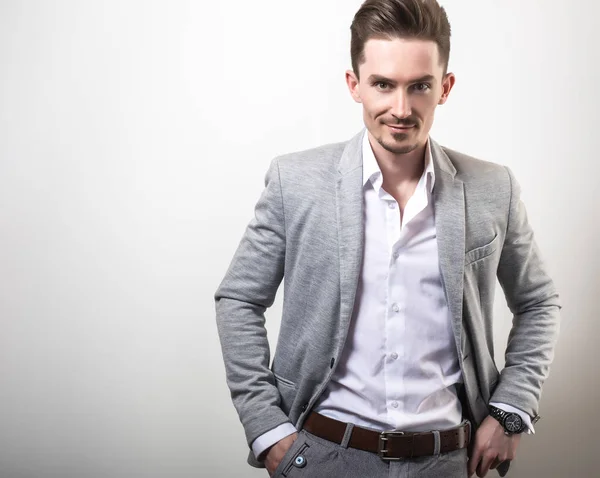 Guapo joven elegante hombre en gris chaqueta pose sobre fondo de estudio . —  Fotos de Stock