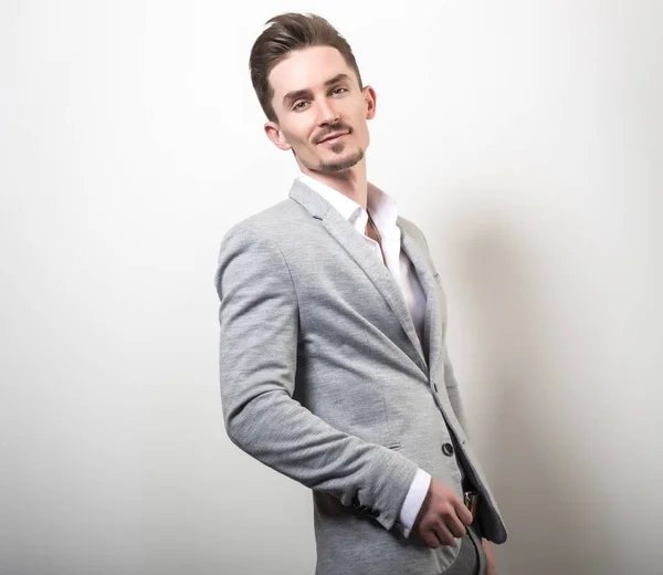 Beau jeune homme élégant en veste grise pose sur fond de studio . — Photo