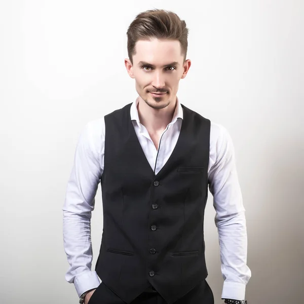 Handsome young elegant man in black classic vest pose against studio background. — Stock Photo, Image