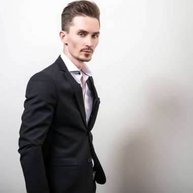 Zarif yakışıklı genç siyah şık klasik kostüm poz studio arka planı.