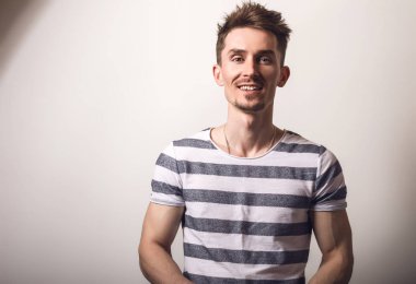 Çizgili gömlekli yakışıklı genç adam poz gri studio arka planı.