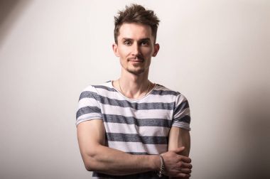 Çizgili gömlekli yakışıklı genç adam poz gri studio arka planı.