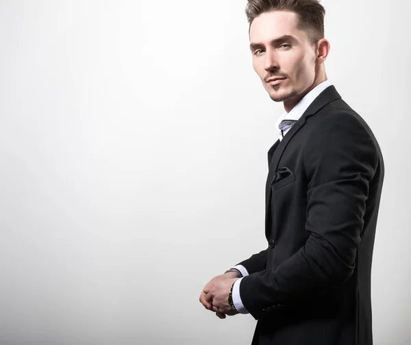 Handsome young elegant man in black stylish classic costume pose against studio background. — Stock Photo, Image