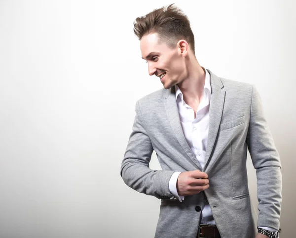 Schöner junger eleganter Mann in grauer Jacke posiert vor Studiohintergrund. — Stockfoto
