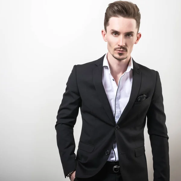 Handsome young elegant man in black stylish classic costume pose against studio background. — Stock Photo, Image