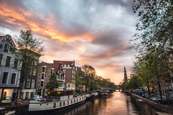 De meest beroemde grachten en ophogingen van Amsterdam tijdens zonsondergang. Algemeen beeld van het stadslandschap en de traditionele architectuur van Nederland. — Stockfoto