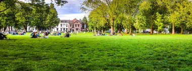 Bir yaz parkta çimlerde oturan insanlar istirahat.