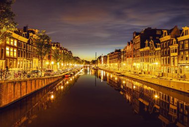 En ünlü kanallar ve gece Amsterdam şehir bentleri. Cityscape ve geleneksel Hollanda mimarisinin genel görünümü.
