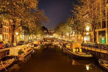 En ünlü kanallar ve gece Amsterdam şehir bentleri. Cityscape ve geleneksel Hollanda mimarisinin genel görünümü.