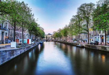 En ünlü kanallar ve bentleri Amsterdam City günbatımı sırasında. Cityscape ve geleneksel Hollanda mimarisinin genel görünümü.