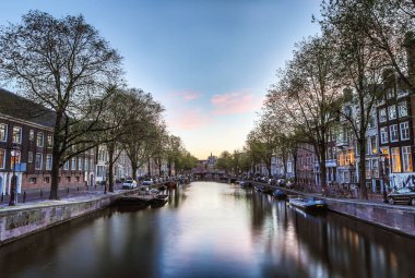 En ünlü kanallar ve bentleri Amsterdam City günbatımı sırasında. Cityscape ve geleneksel Hollanda mimarisinin genel görünümü.