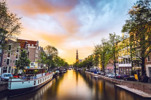 De meest beroemde grachten en ophogingen van Amsterdam tijdens zonsondergang. Algemeen beeld van het stadslandschap en de traditionele architectuur van Nederland. — Stockfoto