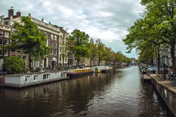 De meest beroemde grachten en ophogingen van Amsterdam tijdens zonsondergang. Algemeen beeld van het stadslandschap en de traditionele architectuur van Nederland. — Stockfoto