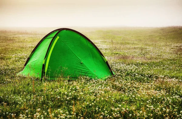 Green travel tent on the field.