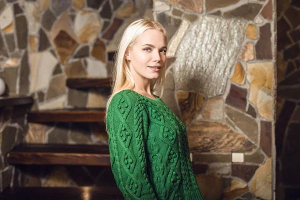 Fiatal szőke szépség nő ellen a ház belső zöld pulóver. — Stock Fotó