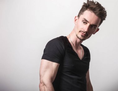 Yakışıklı sportif delikanlı siyah t-shirt poz gri studio arka planı.