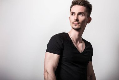 Yakışıklı sportif delikanlı siyah t-shirt poz gri studio arka planı.