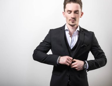 Zarif yakışıklı genç siyah şık klasik kostüm poz studio arka planı.