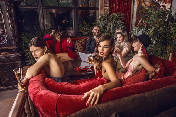 Group of young stylish people dressed classical style in interior of luxury club. — Stock Photo, Image