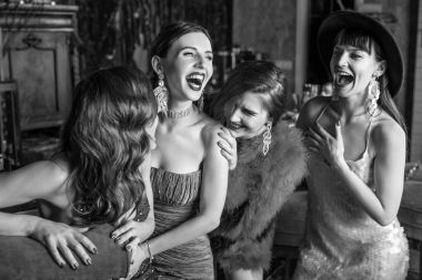 Group of young laughing stylish girls dressed classical style in interior of luxury club. Black-white photo. clipart