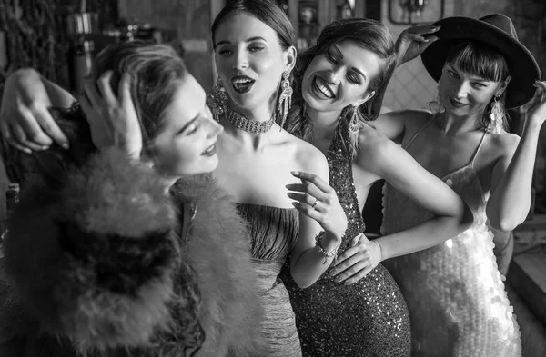 Group of young laughing stylish girls dressed classical style in interior of luxury club. Black-white photo. — Stock Photo, Image