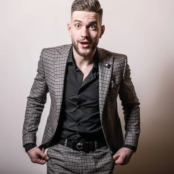 Handsome young elegant man in grey jacket pose against studio background. — Stock Photo, Image