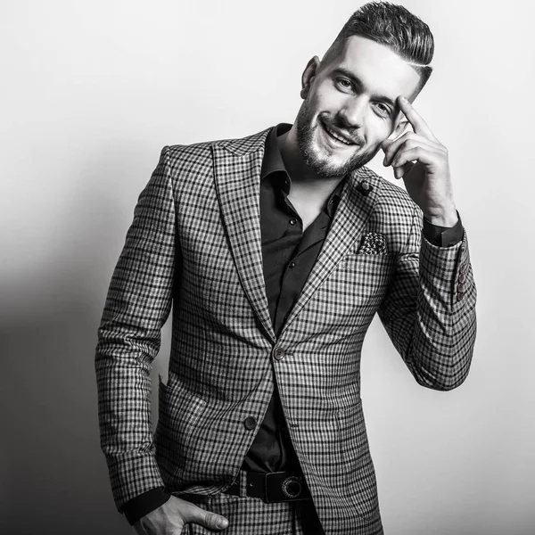 Handsome young elegant man in grey jacket pose against studio background. Black-white portrait. — Stock Photo, Image