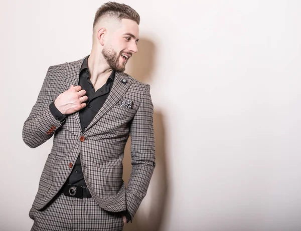 Bonito jovem elegante homem de jaqueta cinza pose contra o fundo do estúdio . — Fotografia de Stock