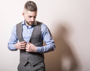 Zarif yakışıklı genç gri klasik yelek içinde poz studio arka planı.