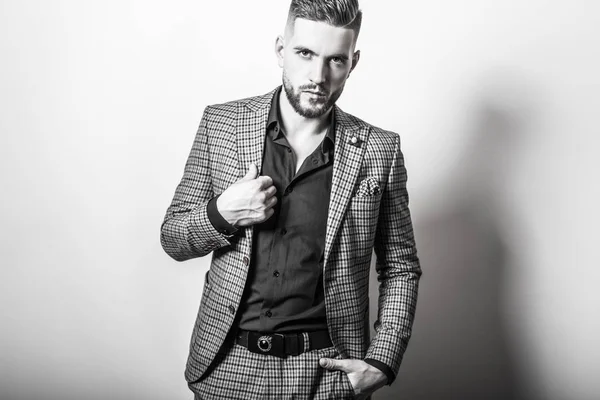 Bello giovane uomo elegante in giacca grigia posa sullo sfondo dello studio. Ritratto bianco-nero . — Foto Stock