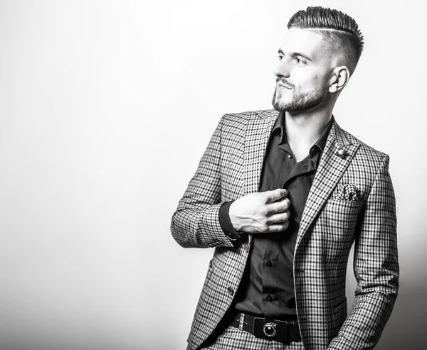 Schöner junger eleganter Mann in grauer Jacke posiert vor Studiohintergrund. Schwarz-Weiß-Porträt. — Stockfoto