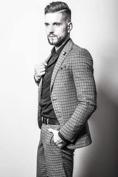 Handsome young elegant man in grey jacket pose against studio background. Black-white portrait. — Stock Photo, Image