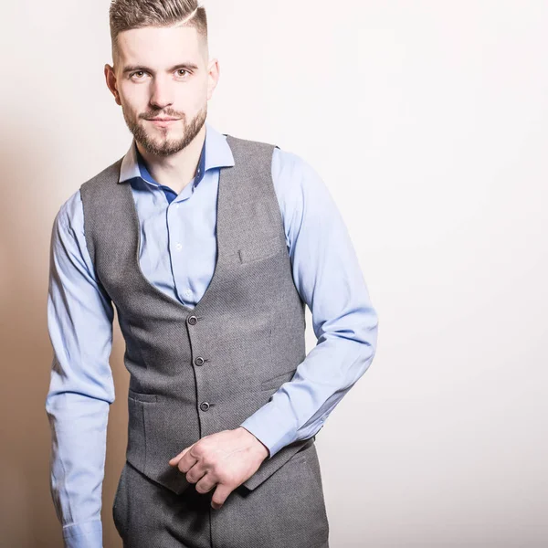 Handsome young elegant man in grey classic vest pose against studio background. — Stock Photo, Image